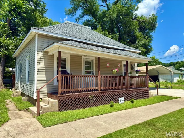 View of front of property featuring roof with shingles, a porch, and a carport