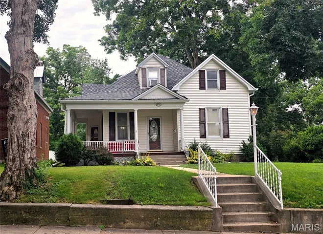 View of front of property featuring covered porch, a front lawn, and a shingled roof
