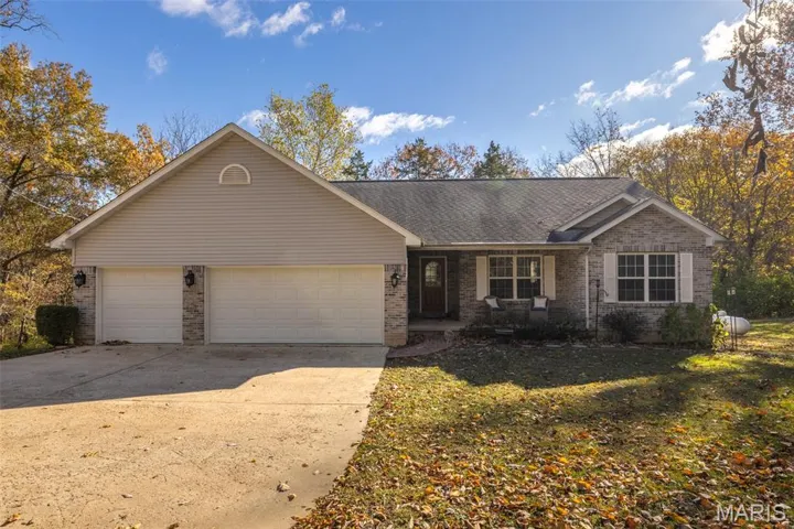 Ranch-style house featuring a porch, brick siding, a shingled roof, driveway, and an attached garage