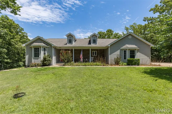 View of front of house with a front yard, roof with shingles, and a porch