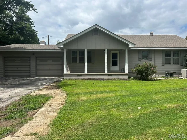 Ranch-style house featuring asphalt driveway, an attached garage, a porch, a front yard, and roof with shingles