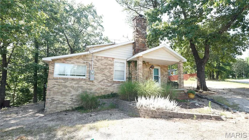 View of front of house featuring brick siding and a chimney