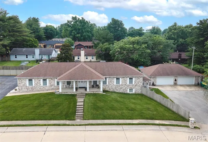 View of front of house featuring a porch, stone siding, driveway, and a detached garage