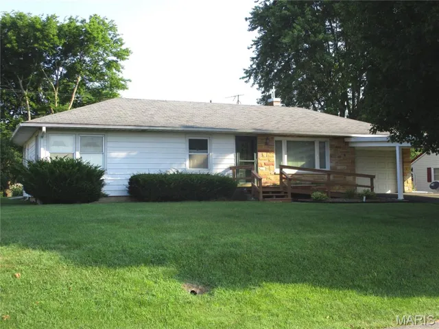 Ranch-style house featuring a garage, a front lawn, a shingled roof, and a chimney