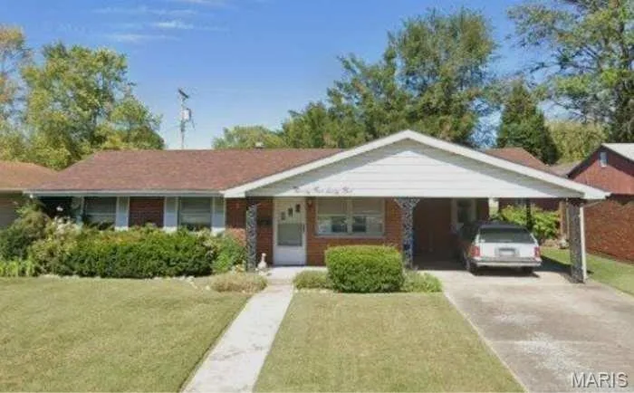 View of front of home featuring driveway, a front yard, an attached carport, and brick siding