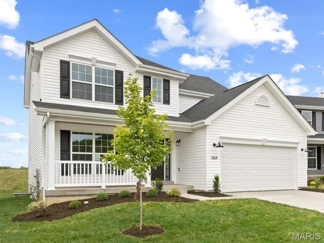 Traditional home with covered porch, concrete driveway, a front yard, and an attached garage