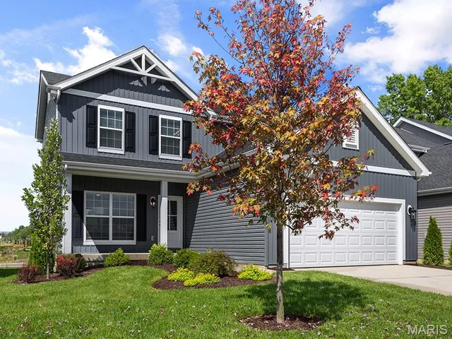 View of front of property with concrete driveway, a front lawn, and a garage