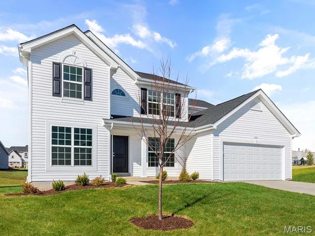 Traditional home with an attached garage, a front yard, and driveway