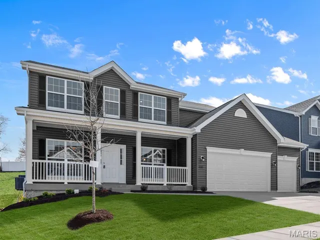 Traditional-style home featuring a porch, a front lawn, driveway, and a garage