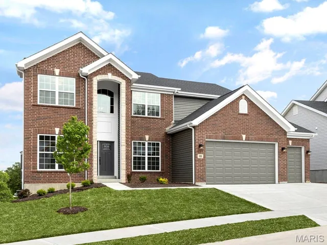 Traditional-style home featuring a garage, brick siding, driveway, and a front yard
