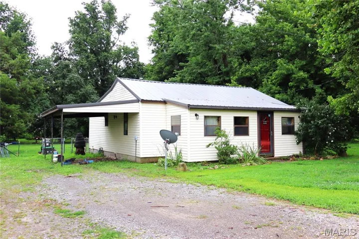 View of front facade with driveway, a front lawn, and a metal roof