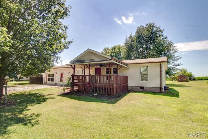 Rear view of house with covered porch, ceiling fan, a yard, crawl space, and a storage shed