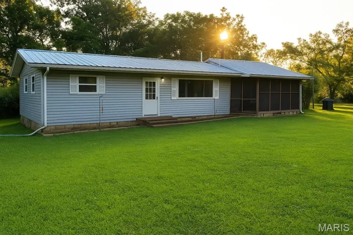 Rear view of property featuring a lawn, a metal roof, entry steps, and a sunroom