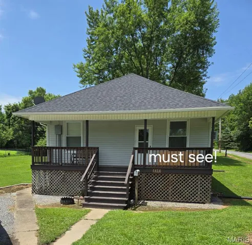 Ranch-style home with roof with shingles, a front yard, a porch, and stairway
