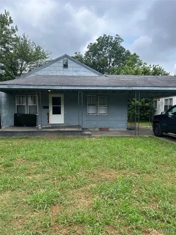 View of front of property with a front lawn, covered porch, a carport, and a shingled roof