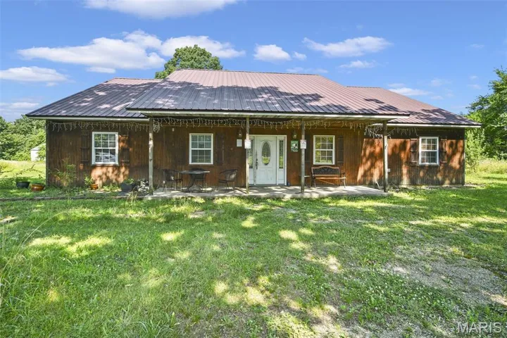 fromt view of house with a lawn and a metal roof