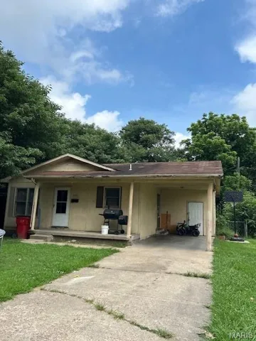 View of front of home featuring driveway, an attached carport, a front yard, and covered porch