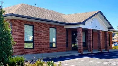 View of front facade with brick siding and uncovered parking