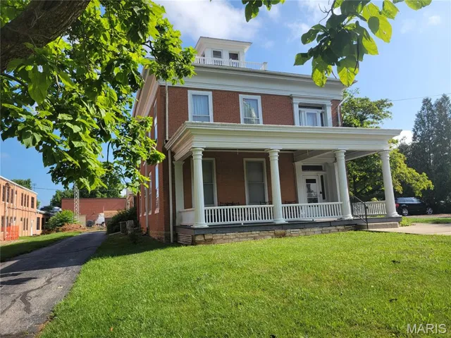 View of front of home featuring a porch, brick siding, and a front yard