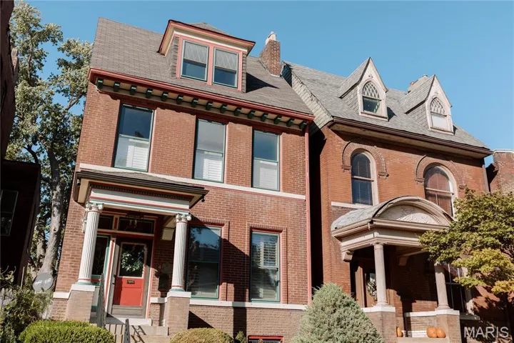 Victorian-style house with brick siding, a chimney, and a shingled roof