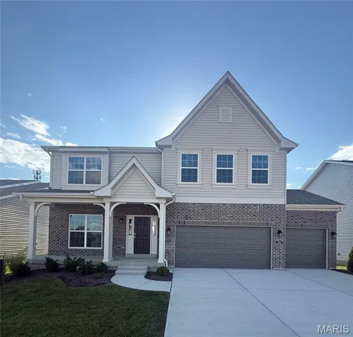 Traditional home with covered porch, brick siding, and concrete driveway