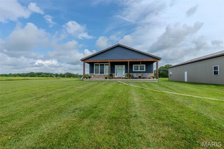 View of front of property featuring a porch, a front lawn, and stone siding