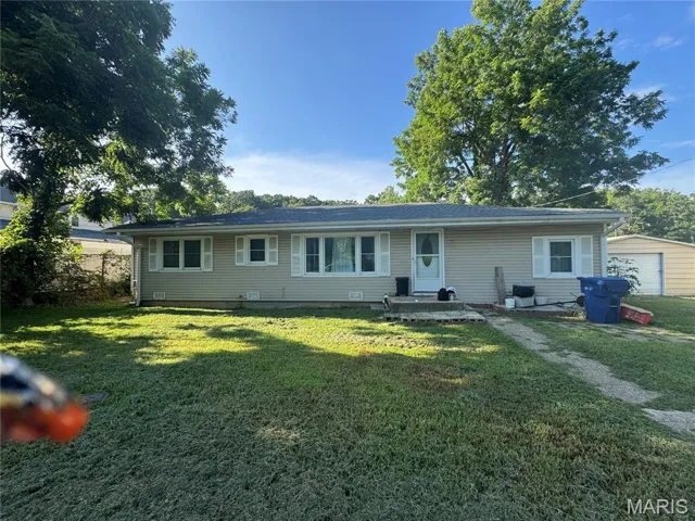 Back of house with a yard, an outbuilding, and a garage