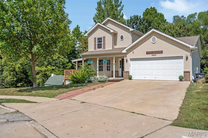 Traditional-style home featuring covered porch, driveway, brick siding, and a garage