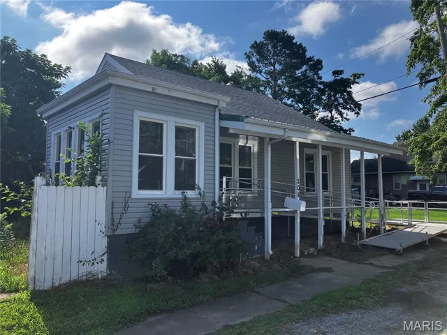 View of front of home featuring a shingled roof and covered porch