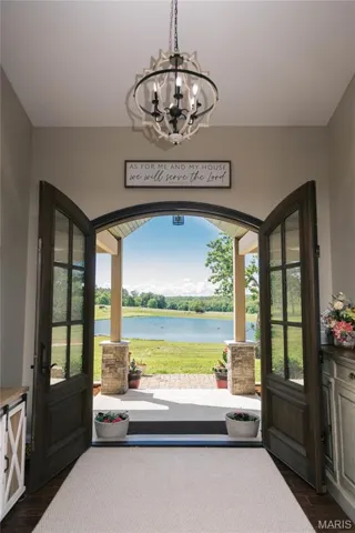 Foyer featuring dark wood-style flooring, a chandelier, and a water view
