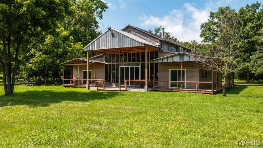 Rear view of house with a deck and a lawn