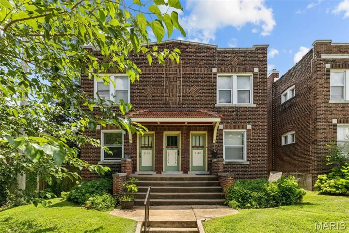 Traditional-style house with brick siding, a front yard, and covered porch