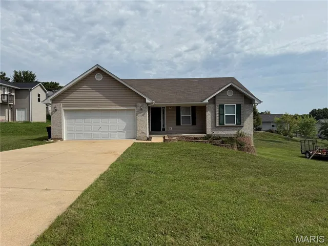 Single story home with a front yard, an attached garage, concrete driveway, and a porch