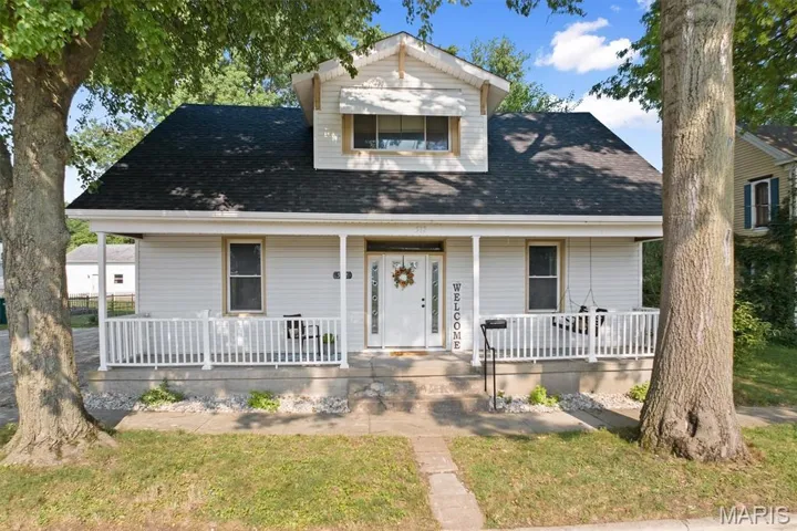 View of front of home with covered porch, roof with shingles, and a front lawn