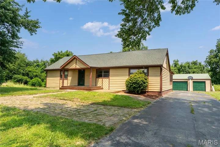 View of front of property featuring a garage, a driveway, a porch, and a front yard