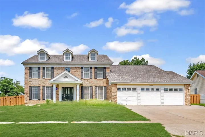 Colonial inspired home with brick siding, a garage, driveway, and roof with shingles