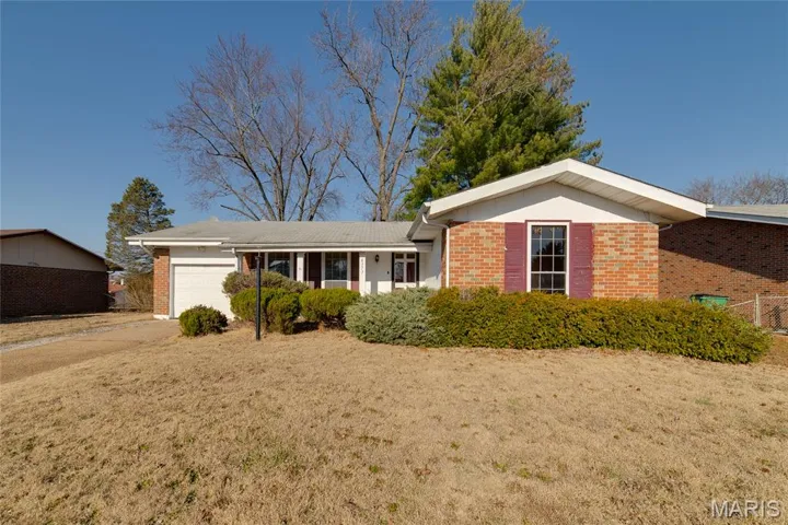 Ranch-style home with brick siding, a garage, concrete driveway, and a front yard