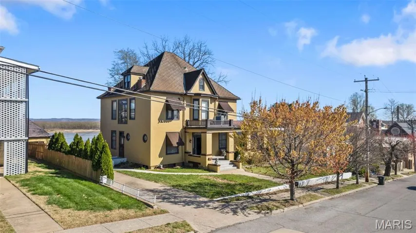 View of front of house featuring a balcony, stucco siding, and a shingled roof