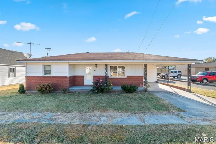 View of front of house featuring brick siding, an attached carport, concrete driveway, and a front yard