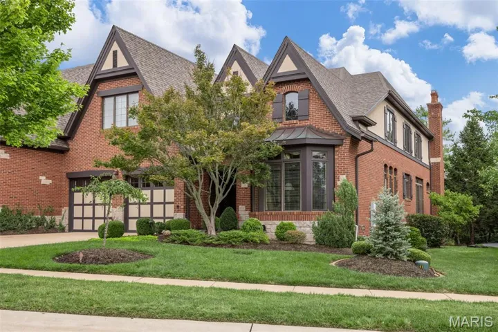 View of front of house with brick siding, a chimney, an attached garage, and a front yard
