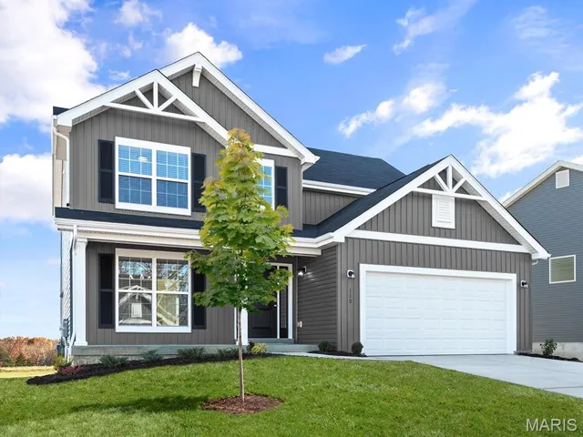 Craftsman-style home with driveway, a front yard, an attached garage, and board and batten siding