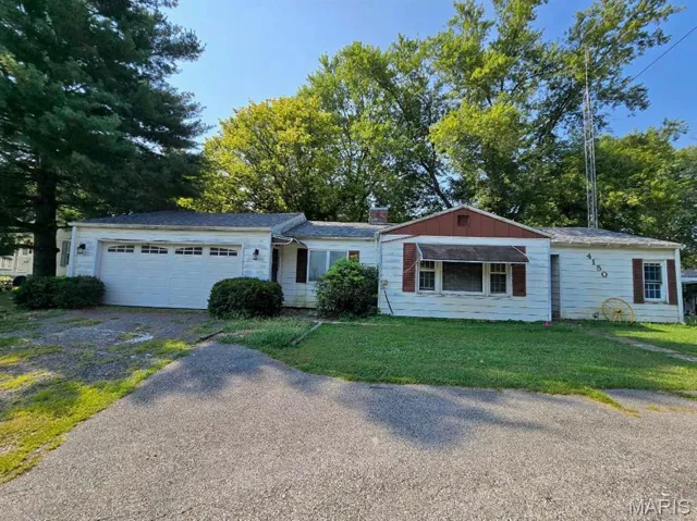 Ranch-style home with an attached garage, gravel driveway, and a front yard