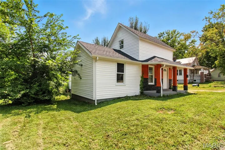 View of front of property with a front yard, a shingled roof, and a porch
