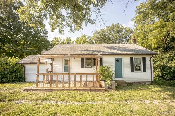 Ranch-style house with a deck, a front lawn, a chimney, and roof with shingles