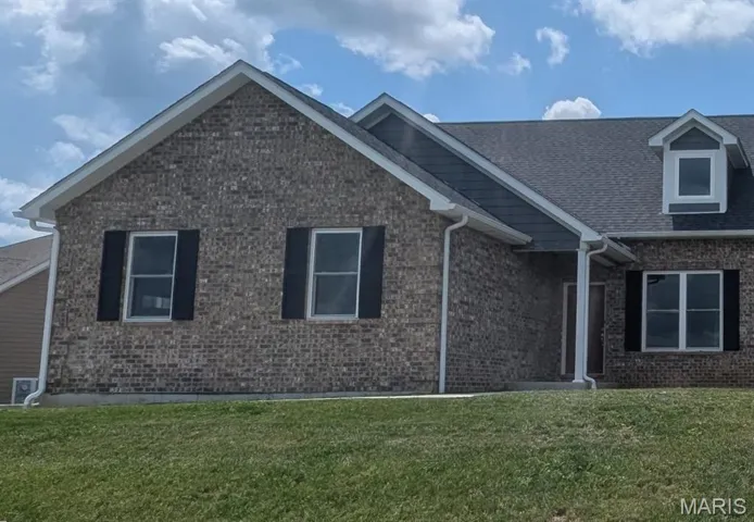 View of front facade with a front lawn, brick siding, and roof with shingles