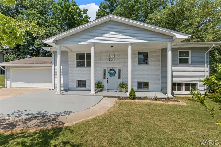 View of front of property with a porch, a front yard, driveway, and brick siding