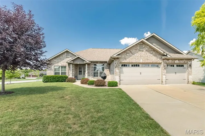 View of front of property with a front lawn, an attached garage, roof with shingles, driveway, and brick siding