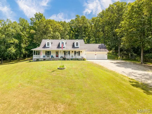 Cape cod home with a porch, driveway, a front yard, and a garage