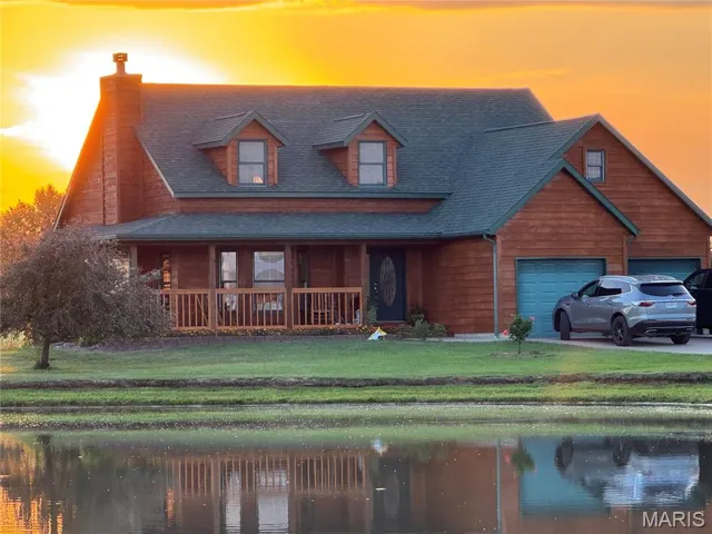 View of front facade with a yard, a chimney, a porch, and a shingled roof