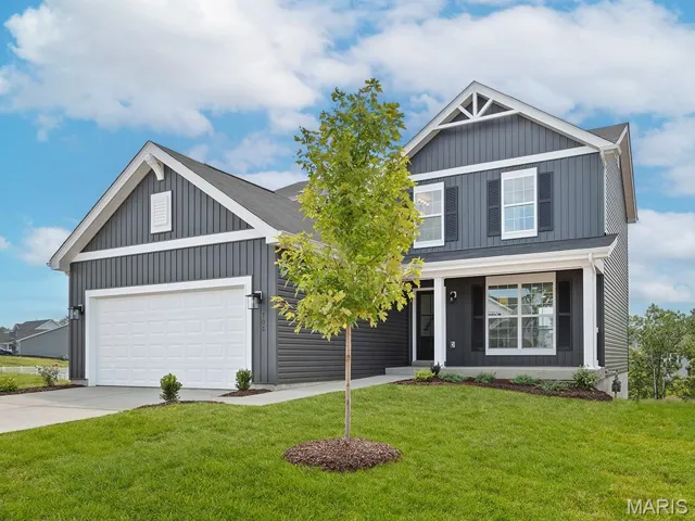 View of front facade featuring a front yard, concrete driveway, a porch, board and batten siding, and an attached garage